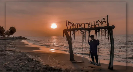 pengunjung sedang berfoto dengan latar sunset di Pantai Cahaya 